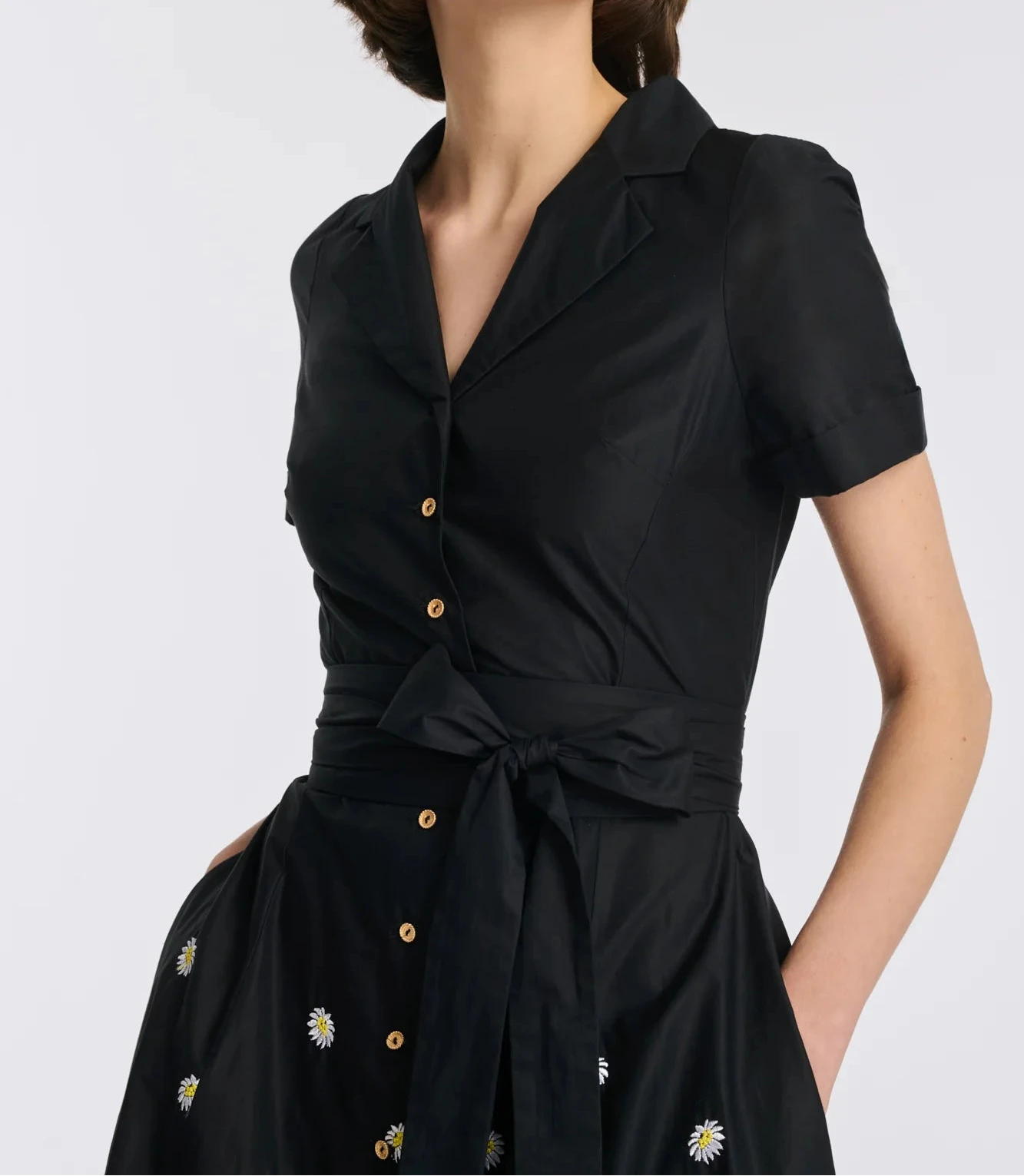 Close-up of black cotton shirt dress with shirt collar, gold buttons, and tie belt on model
