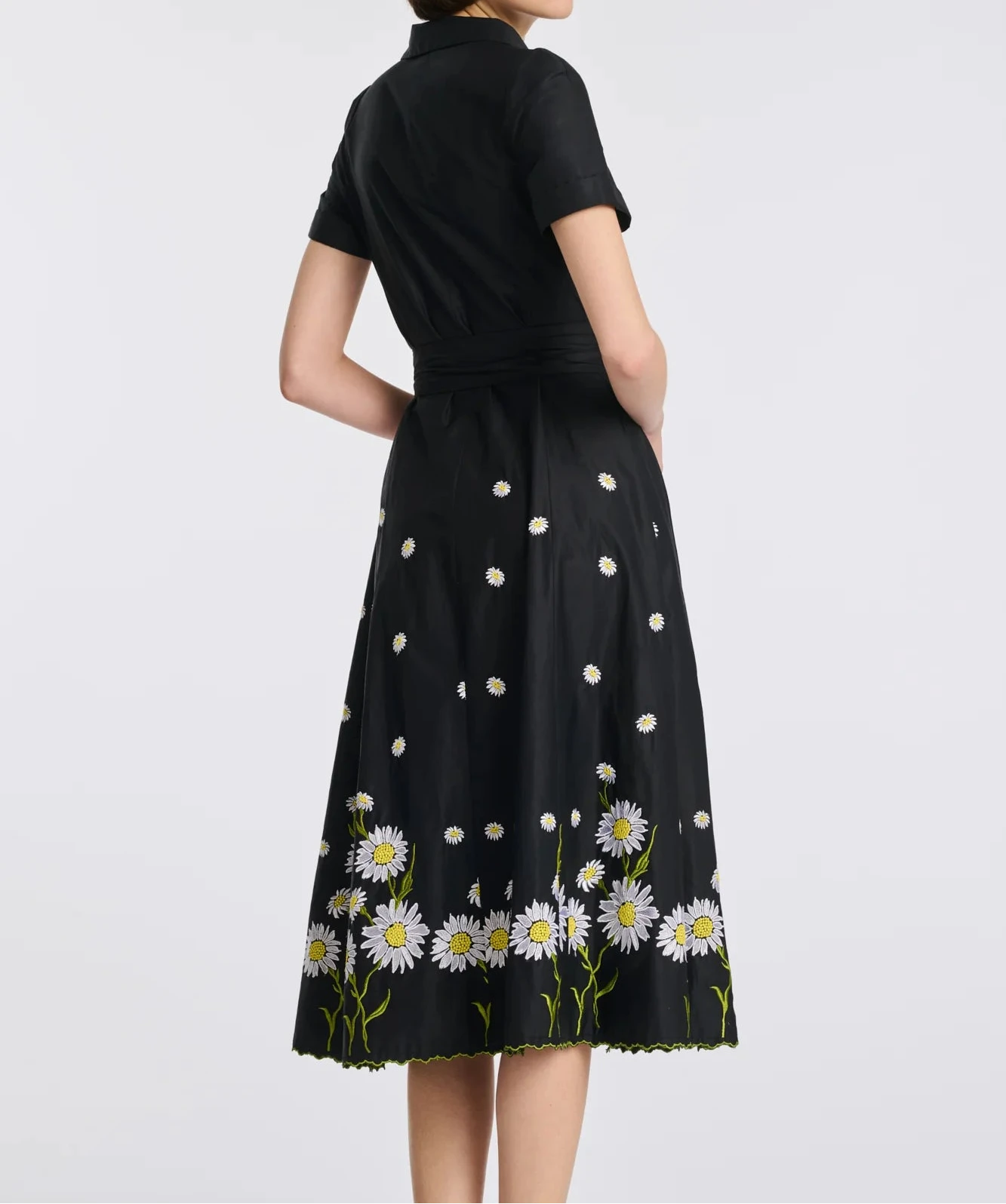 Back angled view of black embroidered cotton midi shirt dress with short sleeves and floral hem detail