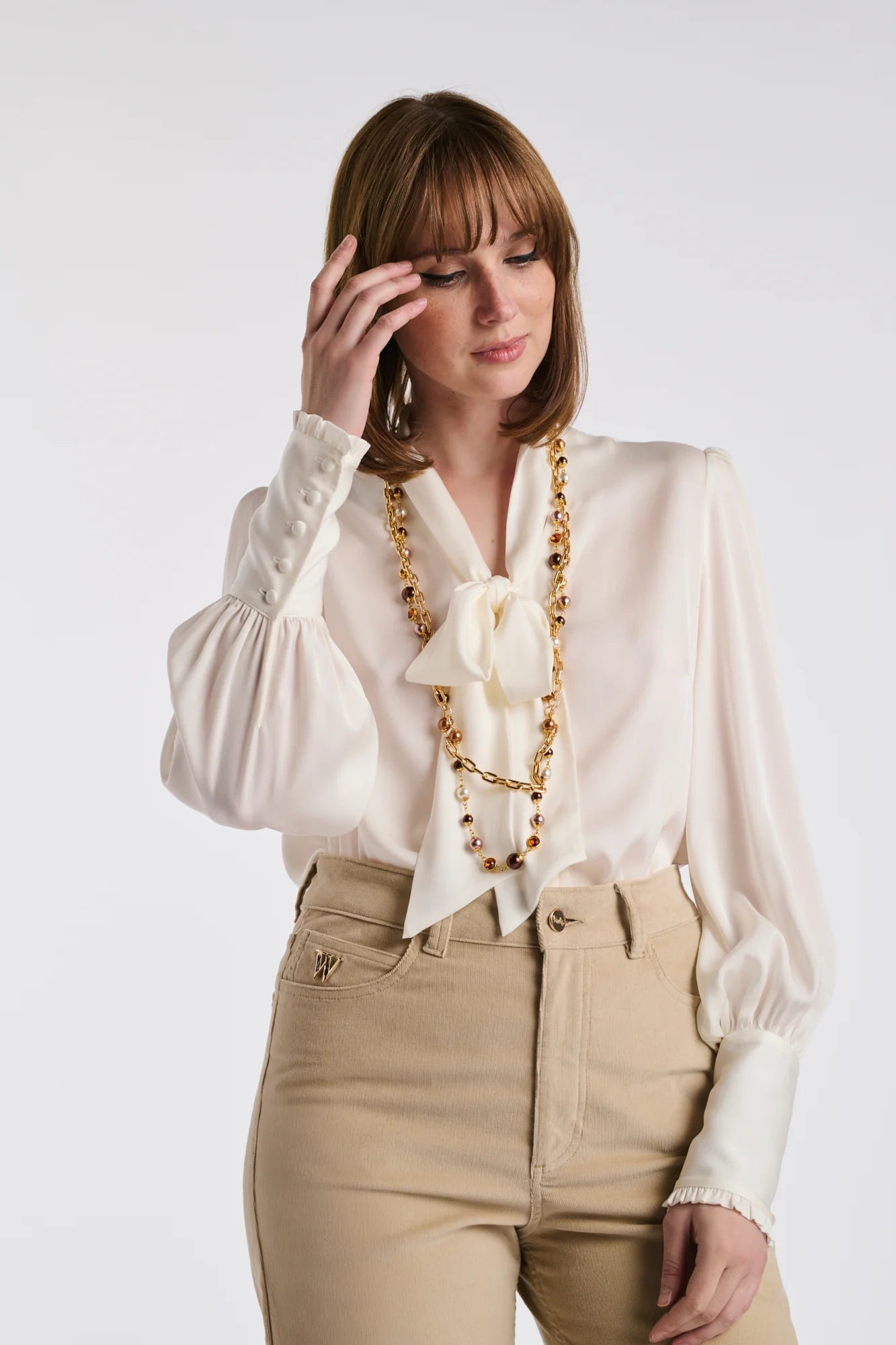 Women wearing a gold double chain pearl necklace styled with a neutral outfit
