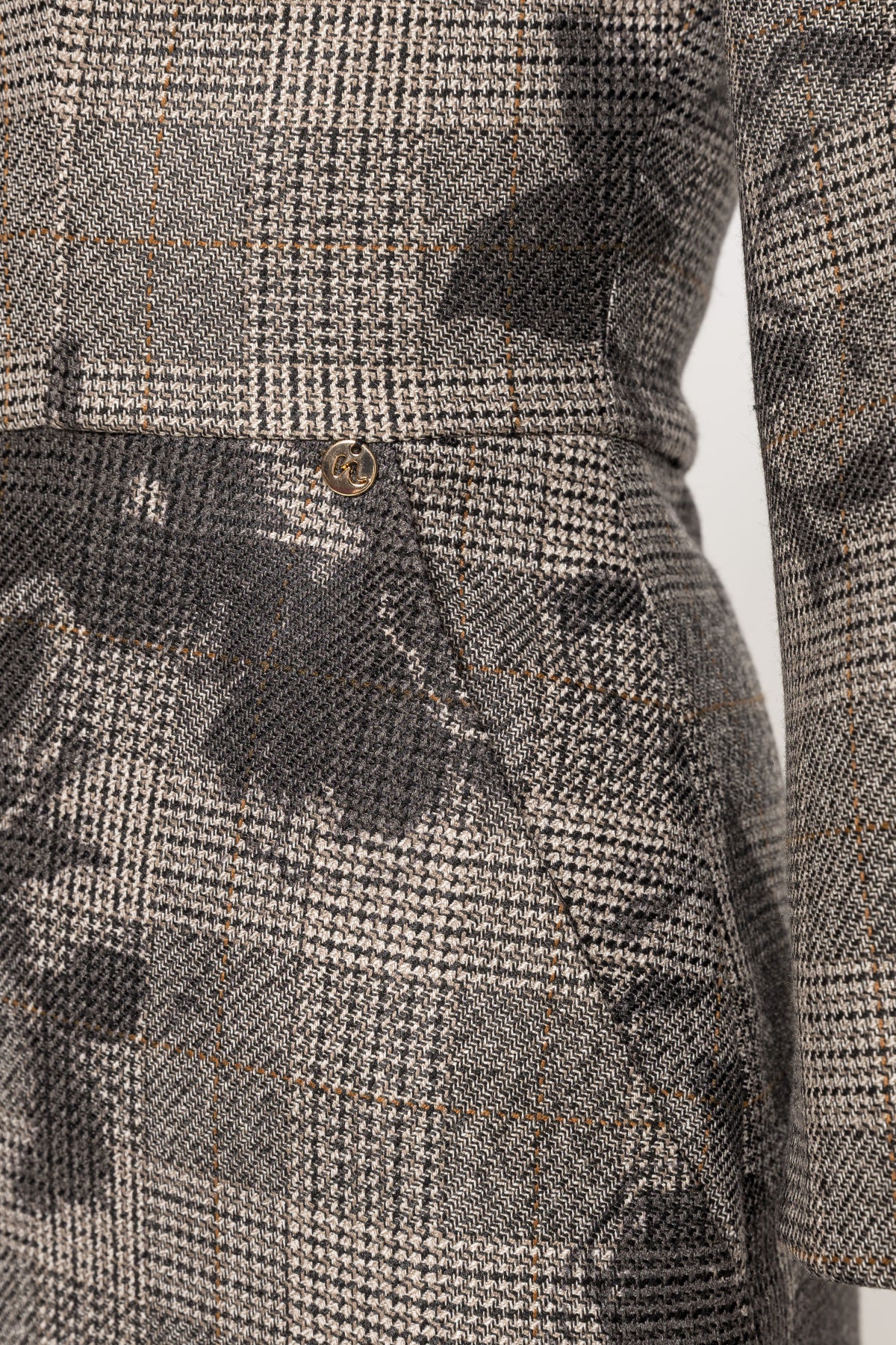 Waist detail of NISSA gray plaid midi dress showing black floral print and a small gold-tone charm.