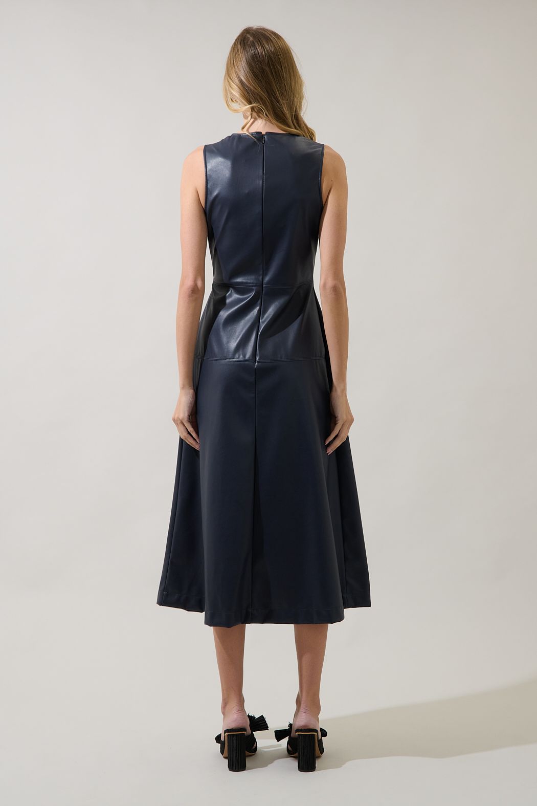 Back view of the Strella navy faux leather midi dress showing a closed back, center zipper and paneled A-line skirt.
