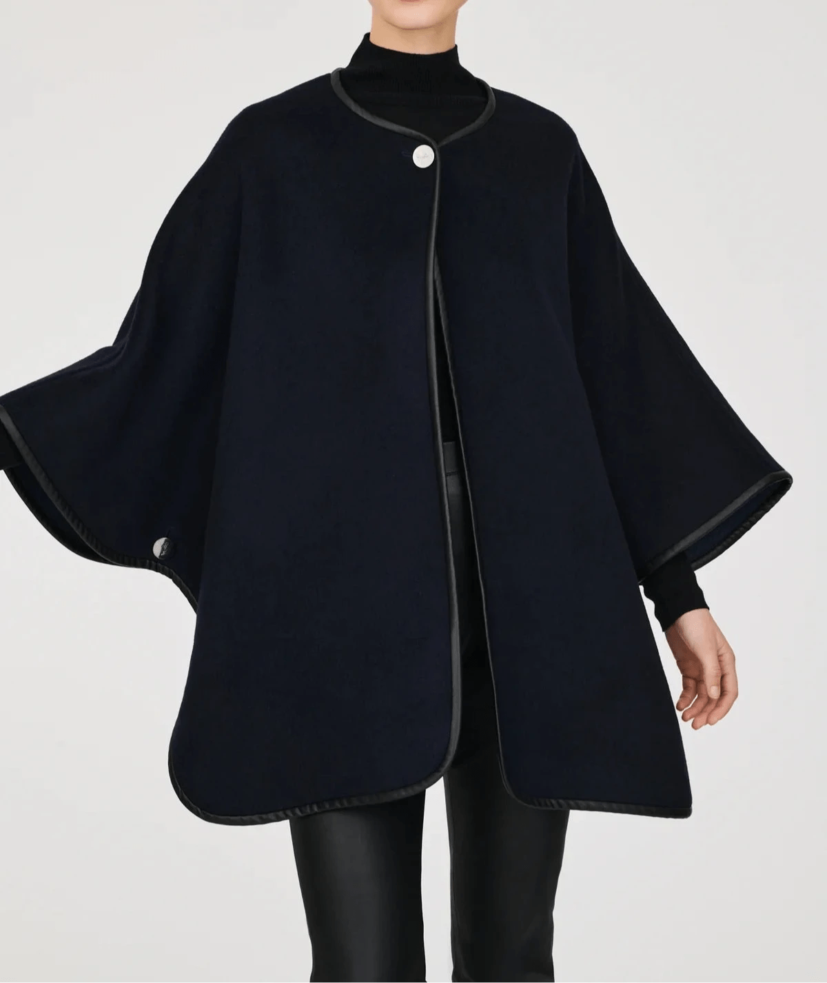 Model wearing Weill Paris reversible navy wool cape with leather trim, styled over black turtleneck and pants – elegant French outerwear for all seasons.