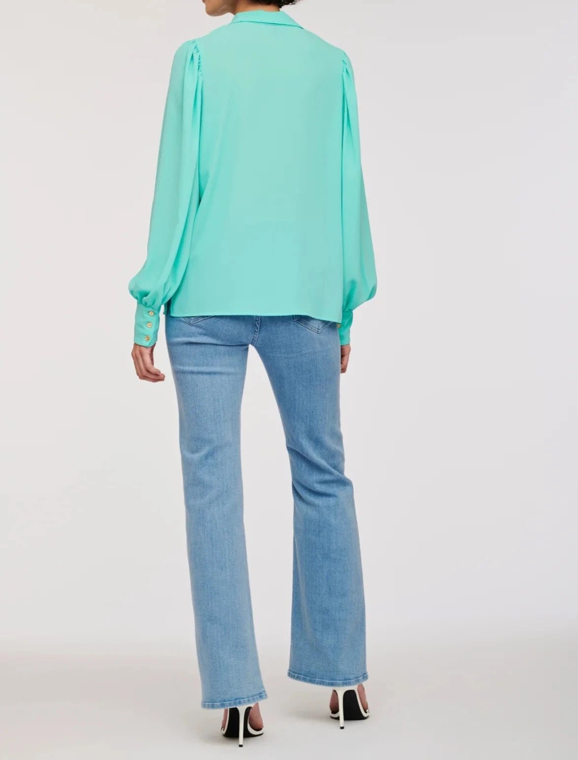 Back view of WEILL turquoise long sleeve blouse worn untucked over blue jeans