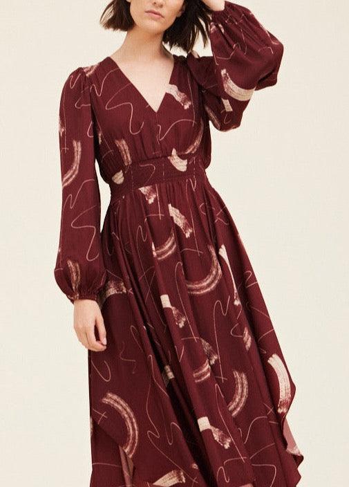 Grade & Gather Vino burgundy abstract satin dress showing the V-neck, smocked waist and long gathered sleeves.