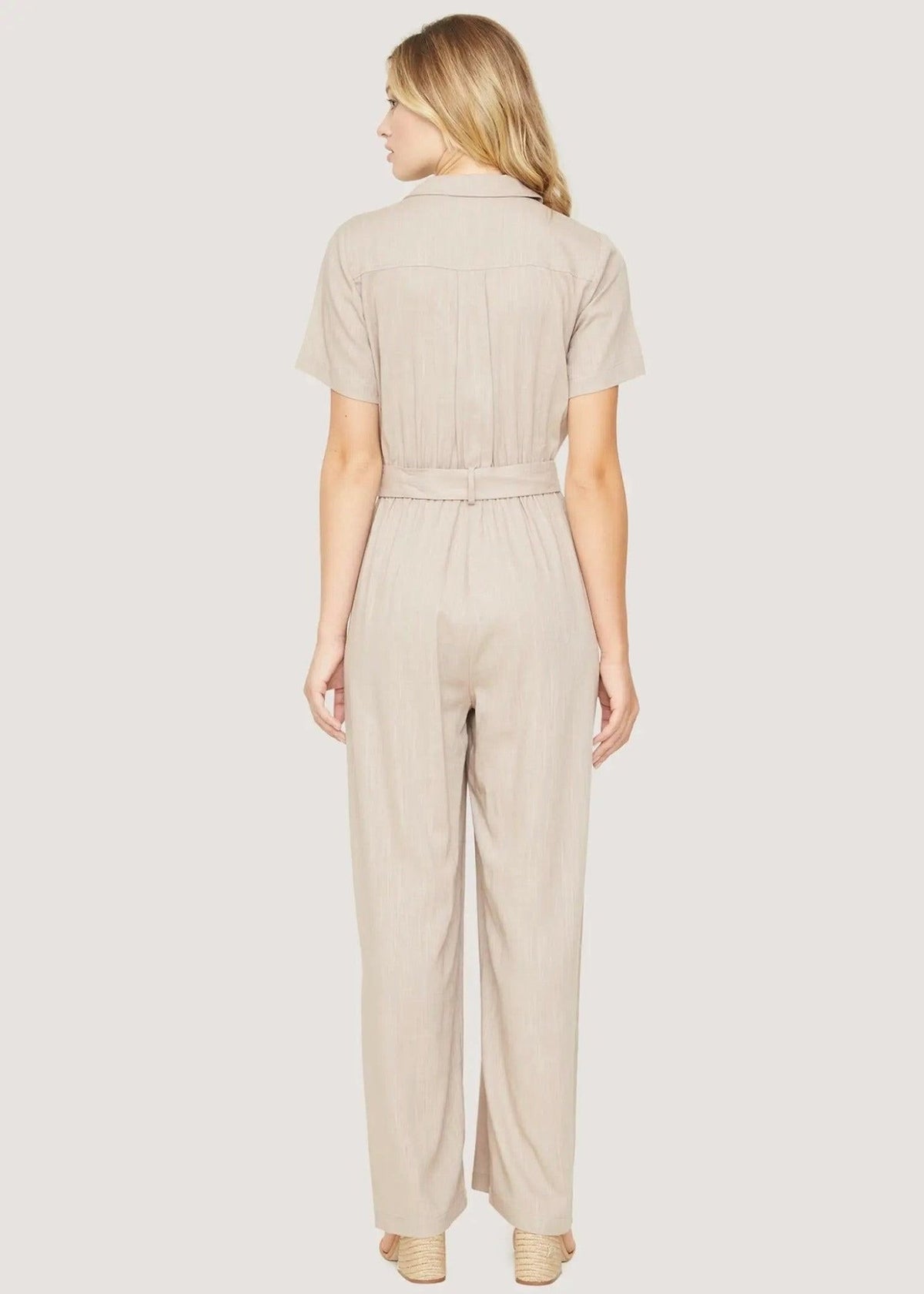 Back view of the Weekend Bliss almond jumpsuit showing short sleeves, a gathered waist and wide legs.