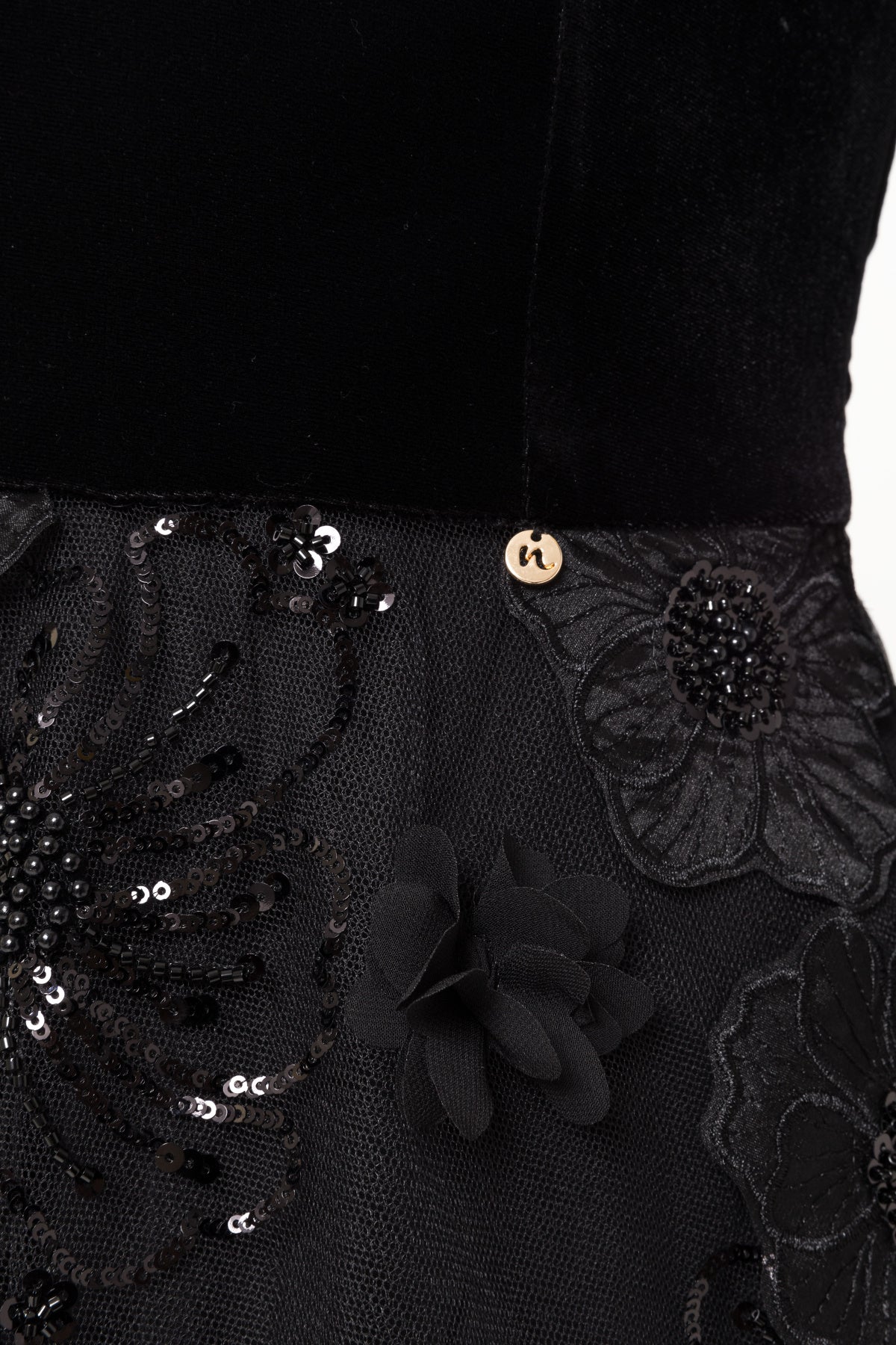 Close‑up of velvet‑to‑tulle seam with sequins and beaded floral appliqué.