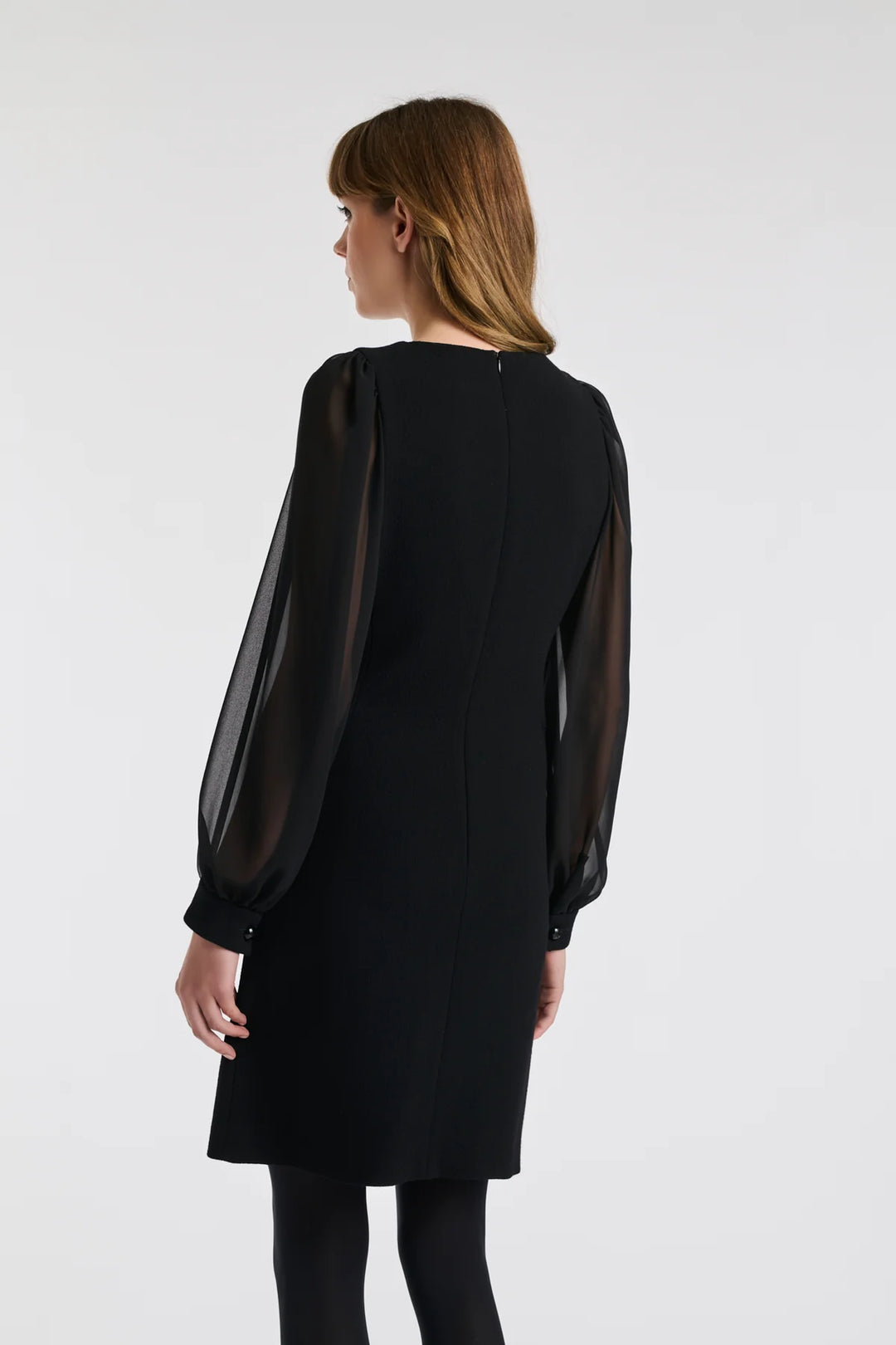 Back three‑quarter: Weill black dress with sheer sleeves, wool crêpe cuffs and concealed back zip.