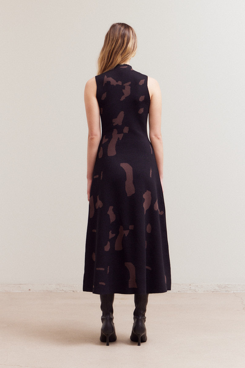 Back view of the same black and brown abstract print maxi dress, showing the high mock neck and A-line skirt flowing to the ankles.