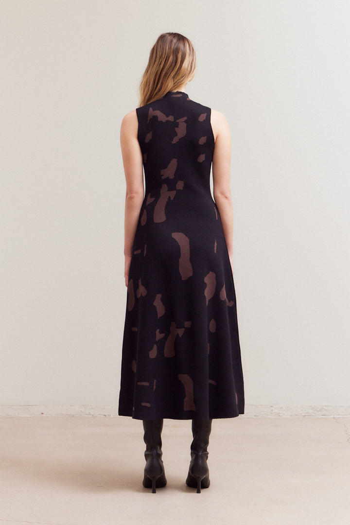 Back view of the same black and brown abstract print maxi dress, showing the high mock neck and A-line skirt flowing to the ankles.