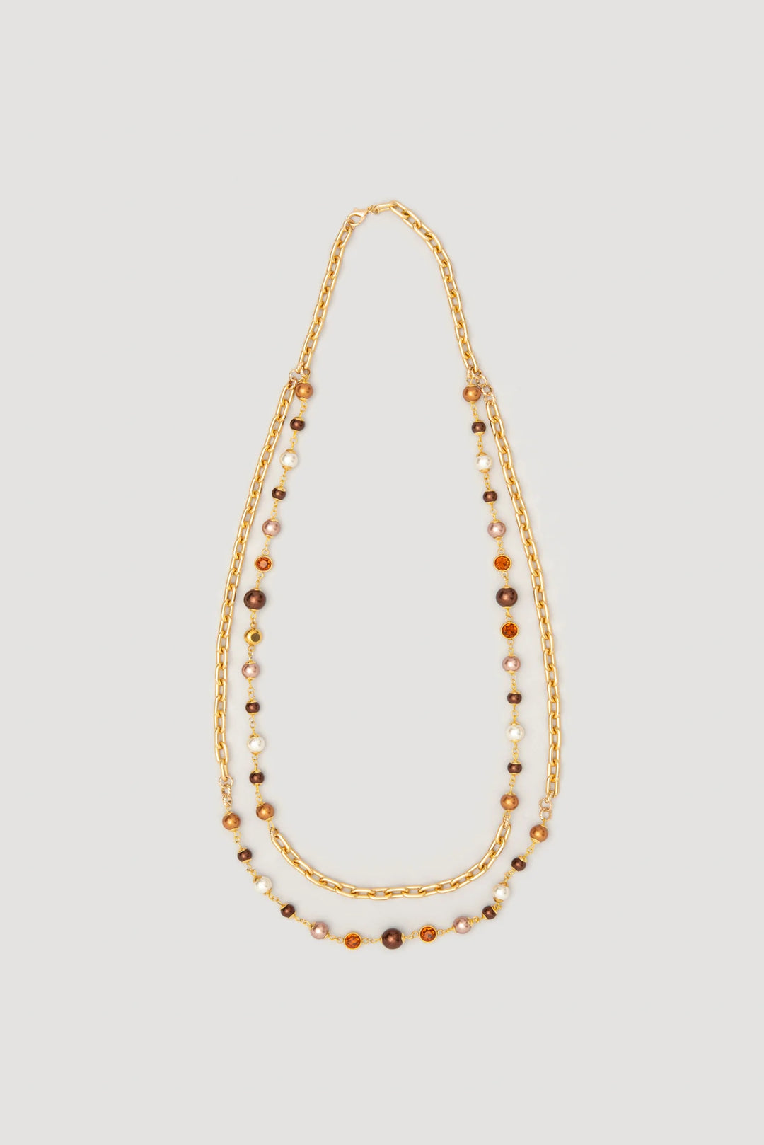 Long double‑chain gold‑tone necklace with brown and pearl‑effect beads and ring details laid flat on a light background.