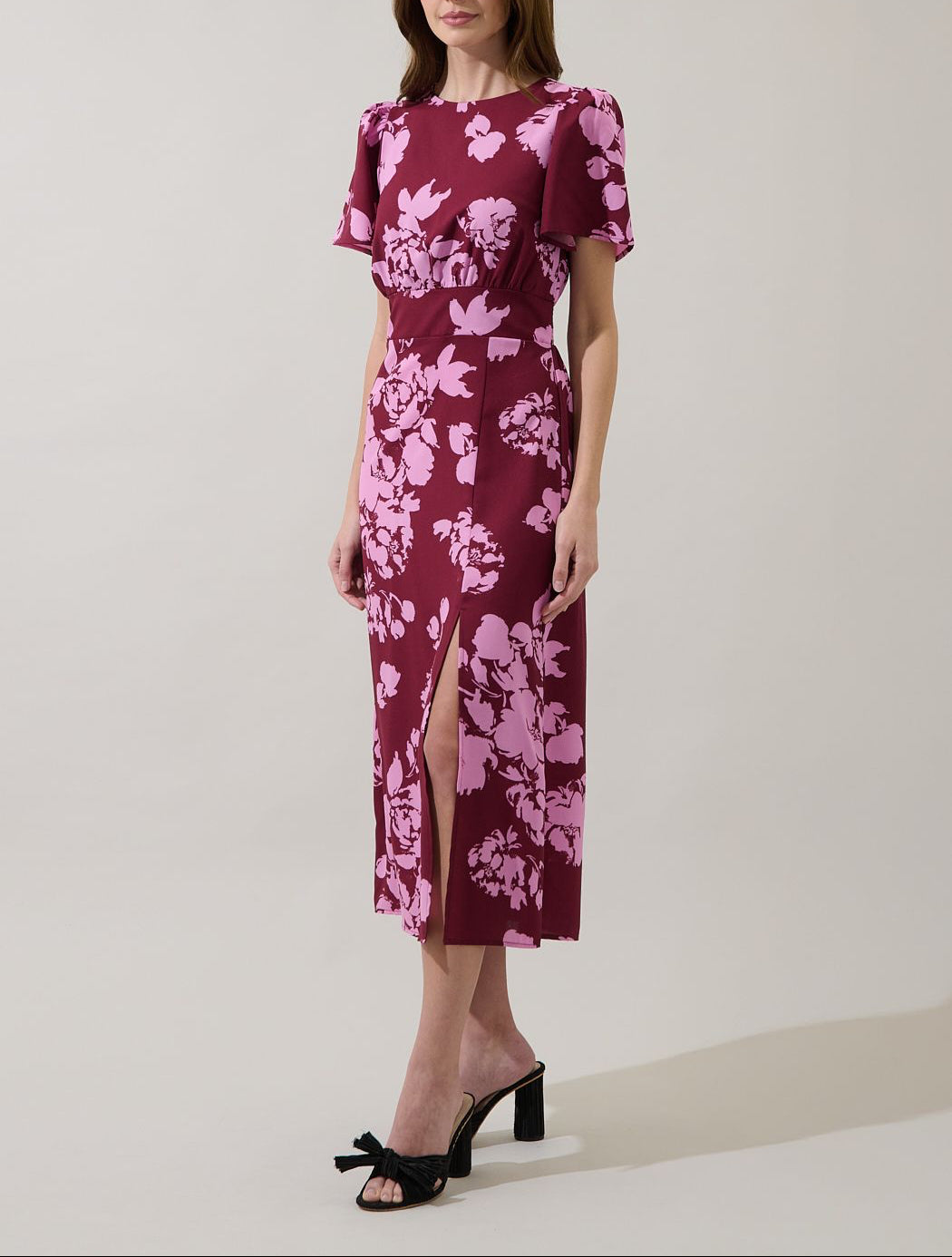 Angled view of the Bloom burgundy floral midi dress showing the defined waist, straight skirt and side slit.