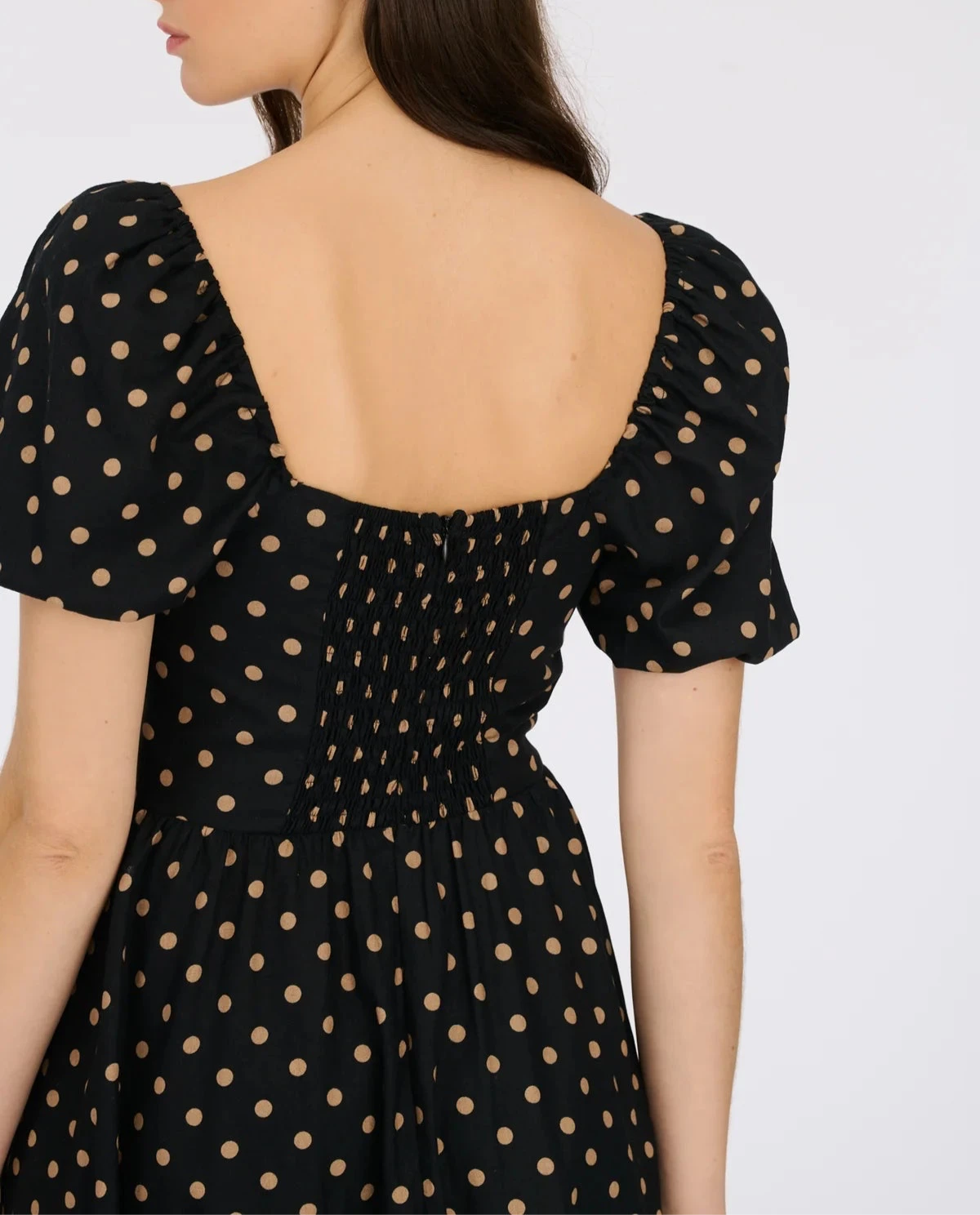 Back view of polka dot midi dress showing elastic shirring and puff sleeve detail