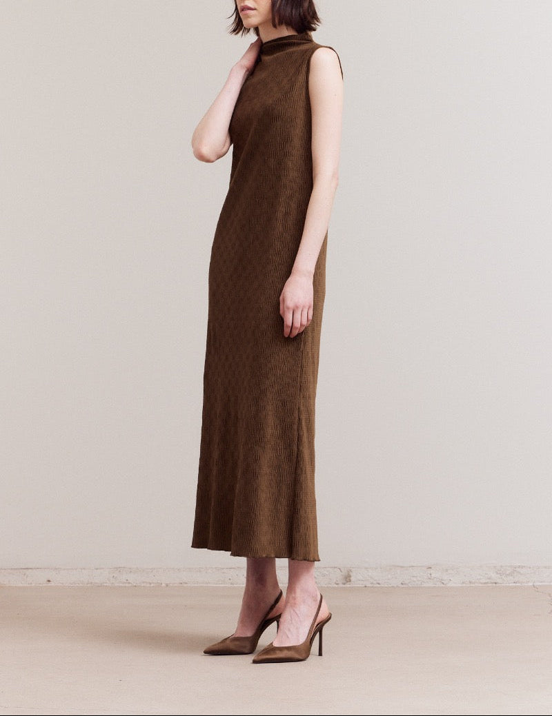 Three‑quarter front view of the dark moss sleeveless crinkled velvet mock‑neck midi dress, model touching her neck to show the soft collar.