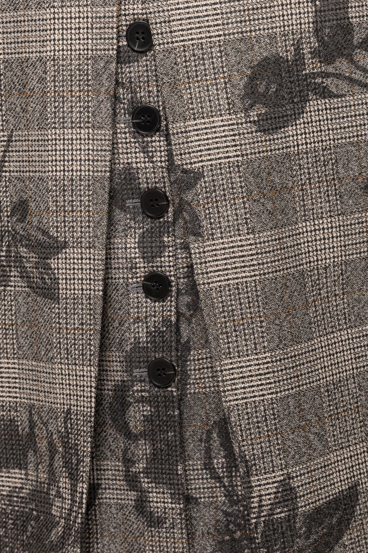 Close-up of black decorative buttons and floral print over the gray plaid back skirt.