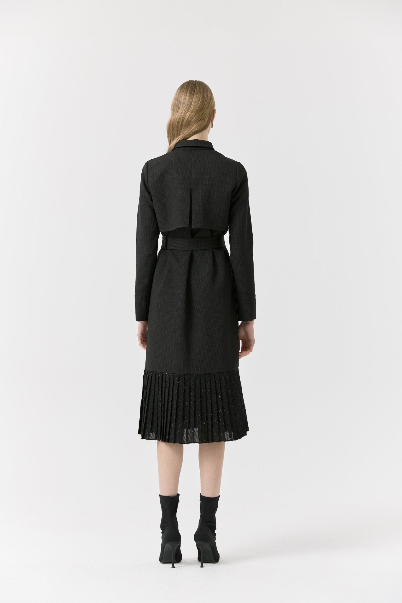 Back view of black midi dress with structured yoke detail and pleated hem.