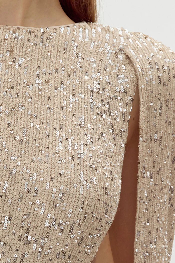 Close‑up of champagne sequins and open cape sleeve detailing on mini dress