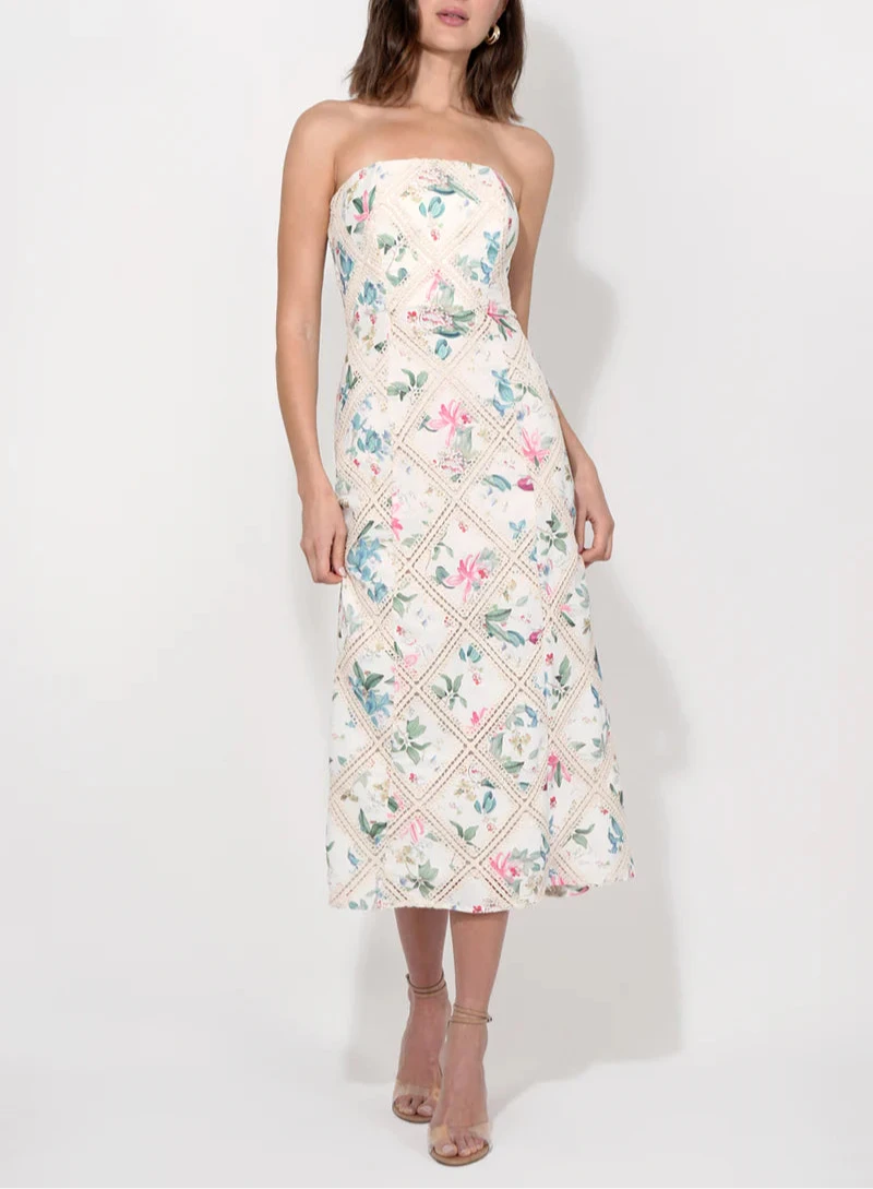A strapless midi dress with floral print and crochet details, in a cream color, modeled by a woman.