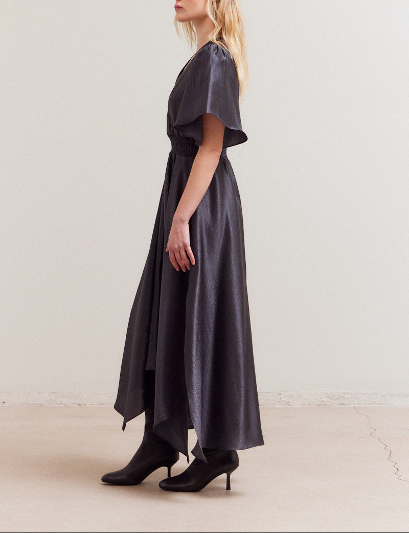 Side profile of Grade & Gather's satin maxi dress showing unbalanced hem and flowy silhouette.