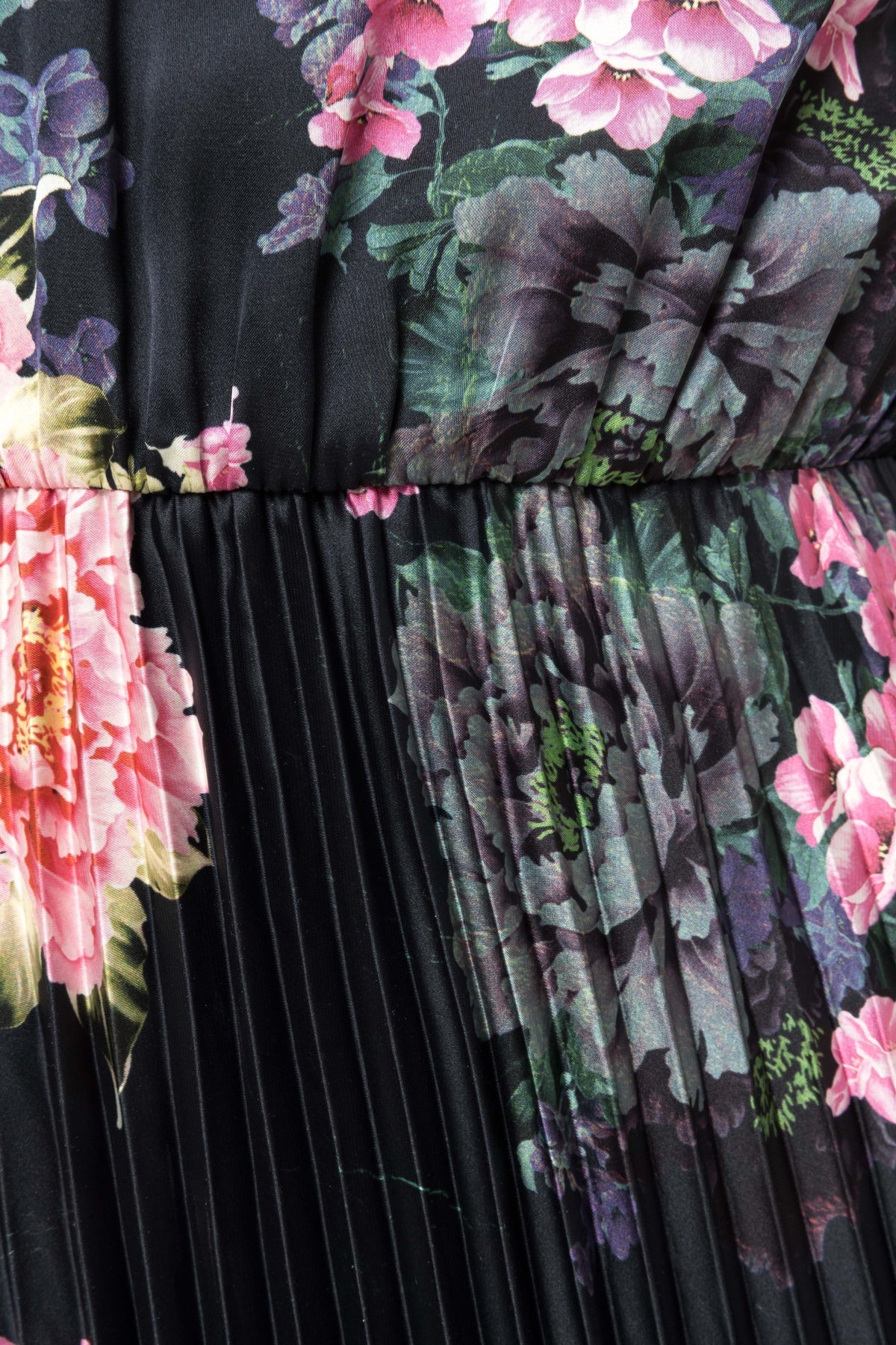 Close‑up of painterly peony floral print and fine knife pleats on black fabric