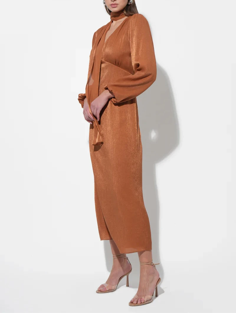 Side view of rust scarf‑neck midi dress showing balloon sleeves and fluid column silhouette.