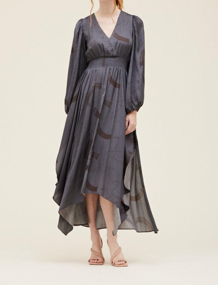 Front view of the Grade & Gather Slate gray abstract satin maxi dress with long sleeves and an asymmetrical hem.