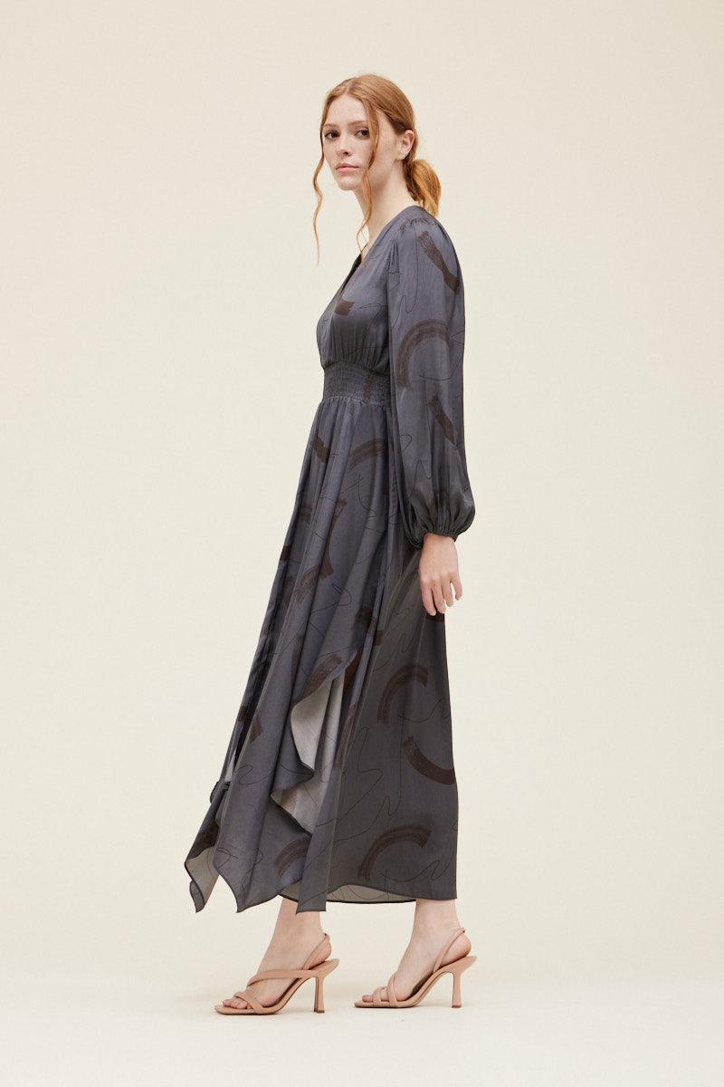 Side view of the Grade & Gather Slate gray satin maxi dress showing the long sleeve and draped uneven hem.