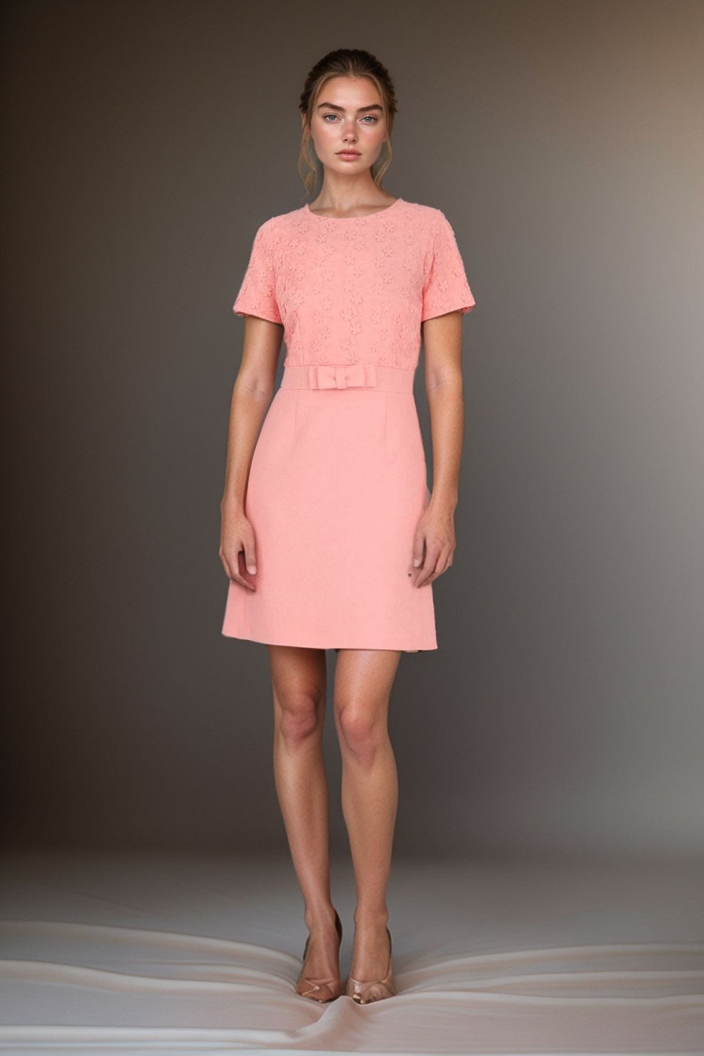 Woman wearing Weill Paris blush pink dress with short sleeves, lace bodice, and waist bow