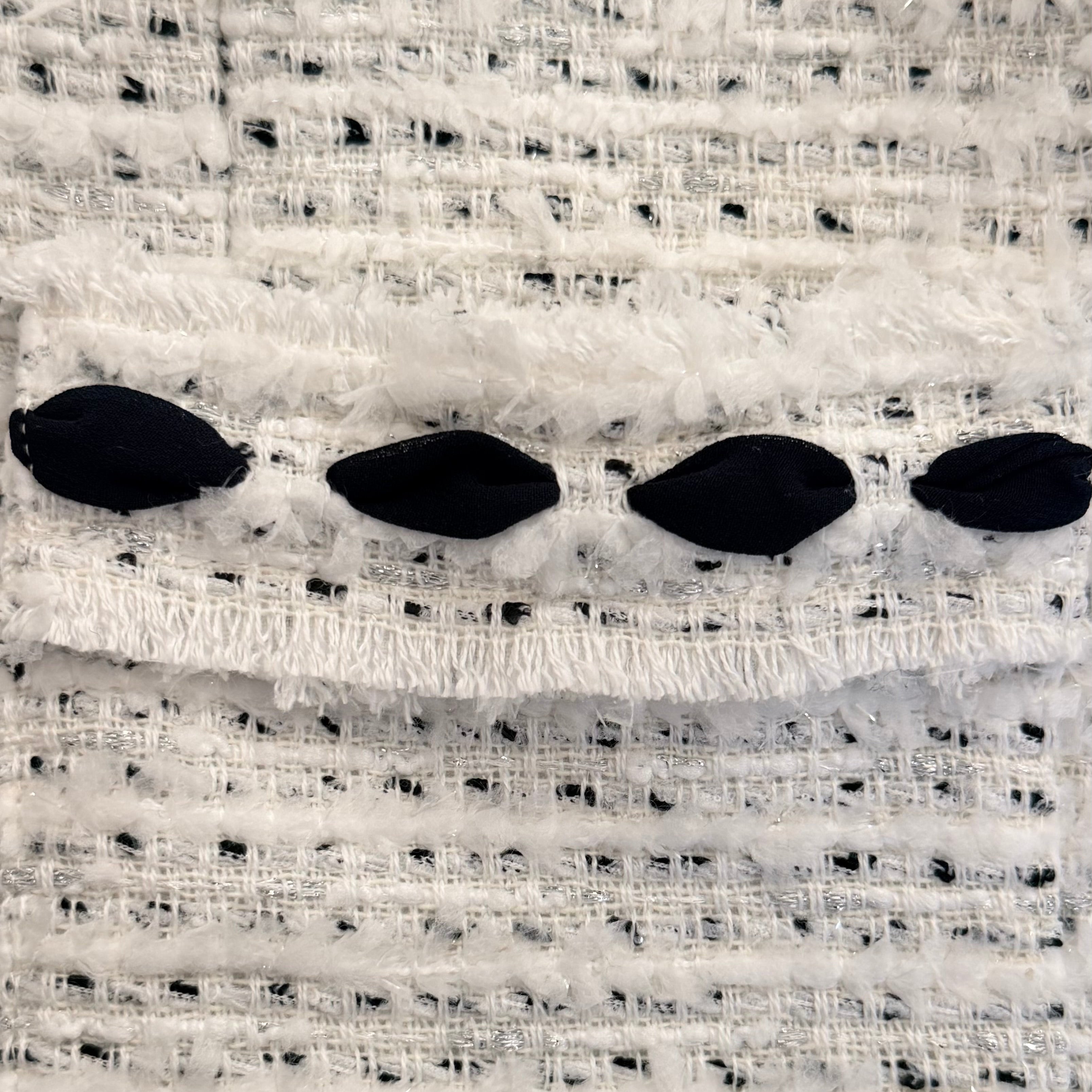 Close-up of the pocket on the Weill Paris ivory bouclé tweed jacket with black contrast trim and textured bouclé fabric