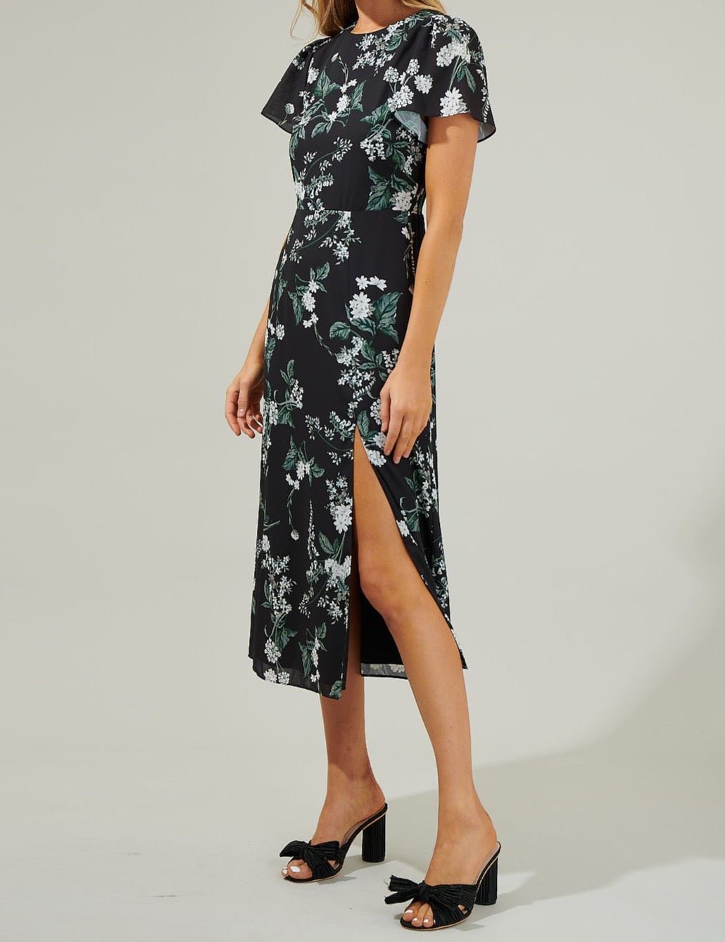 Angled view of the Angelonia floral midi dress showing its defined waist, short flutter sleeves and high slit.