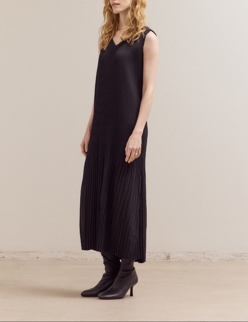 Woman wearing a black sleeveless dress against a plain background