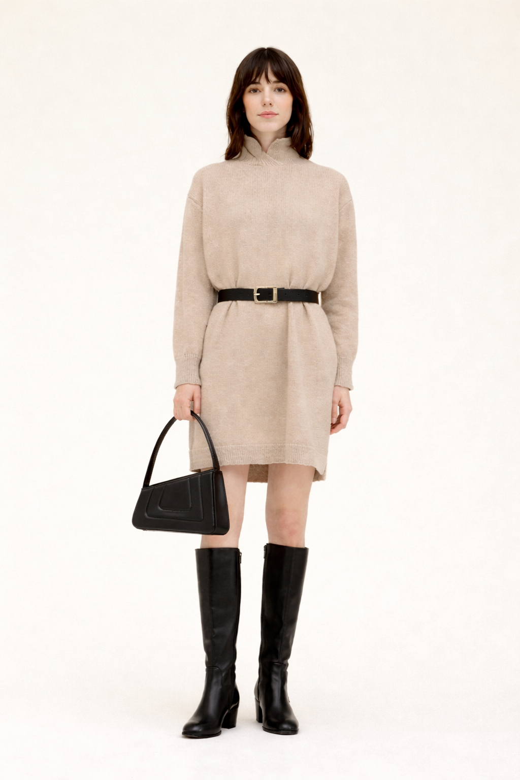 Woman wearing a beige dress with black boots and black Albert small quilted calfskin handbag on a white background