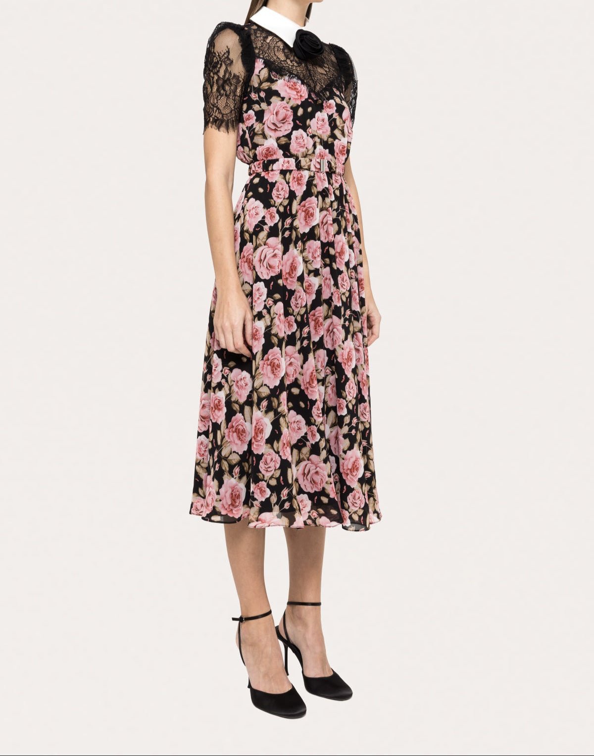Side view of collared black floral midi dress with lace short sleeves, rosette at the neck and a softly flared tea‑length skirt