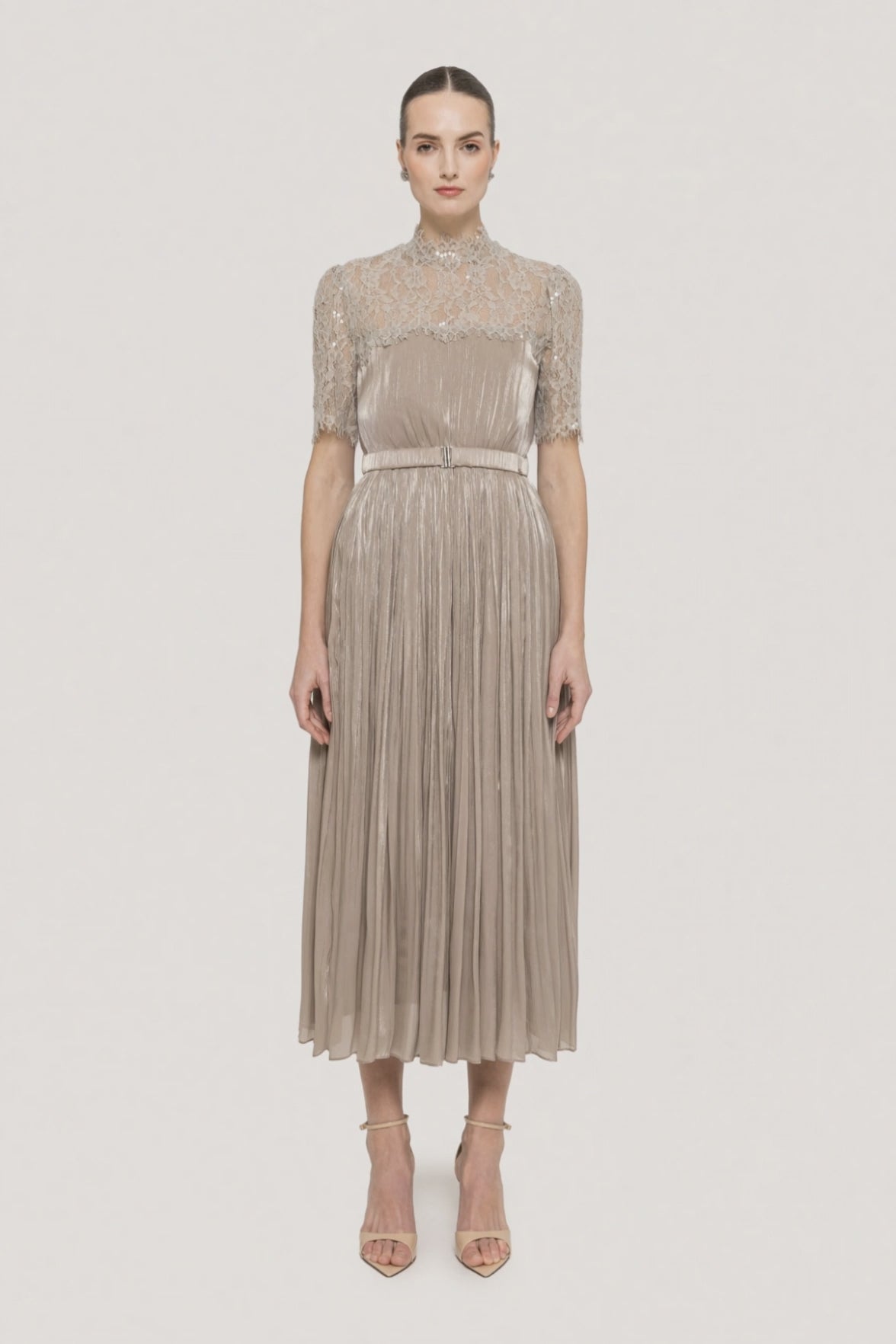 Model wearing a champagne lace high neck metallic pleated midi dress with belt and elbow-length lace sleeves