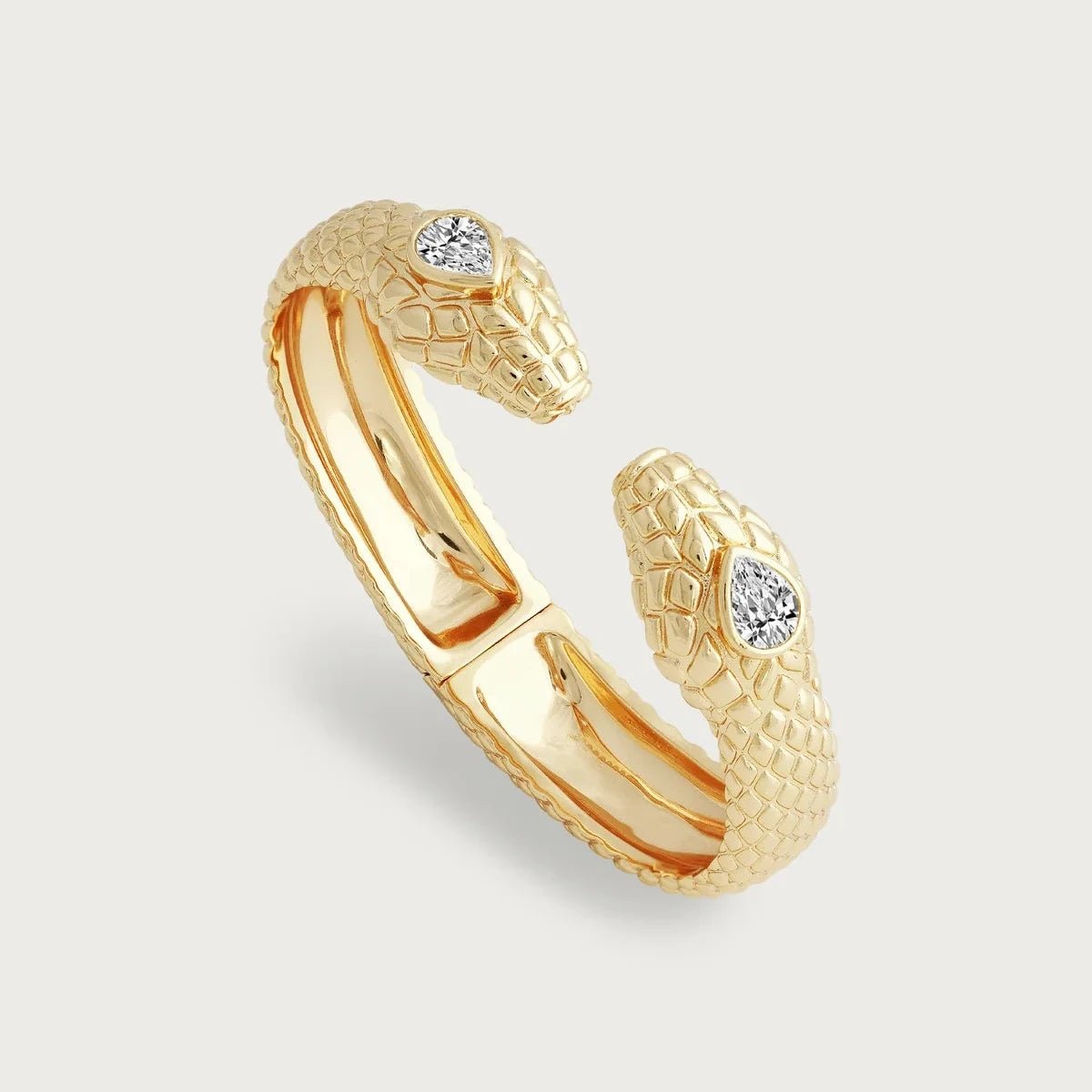 Serpent Double Head Hinged Bracelet by Anabel Aram featuring two gold snake heads with textured scales and crystal eyes, connected by a hinged gold‑plated band.