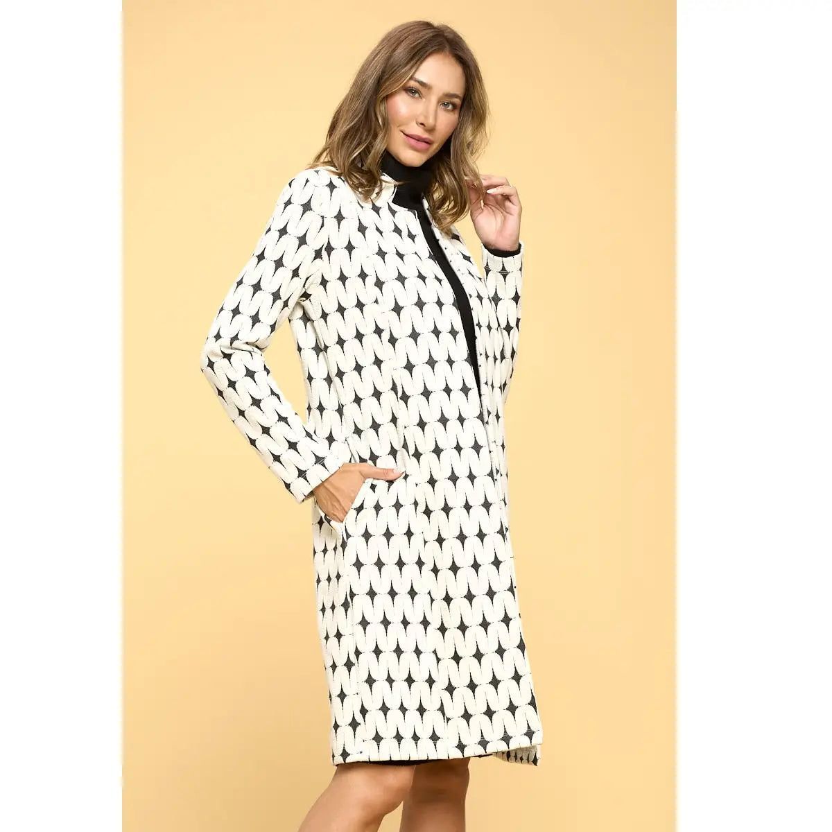 Angled detail of Renee C ivory and black geometric jacket showing a side pocket, long sleeve and short stand collar.