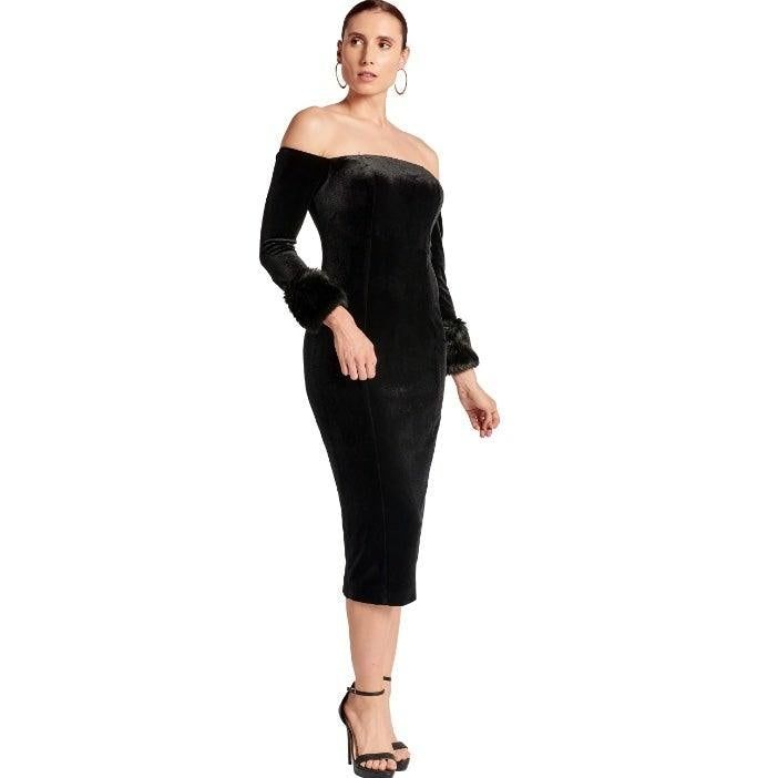 Joia black velvet midi dress with one arm bent, showing the off-the-shoulder neckline and long sleeves with faux-fur cuffs.