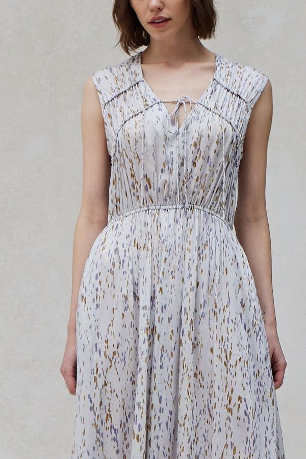 Close‑up of split V‑neck tie and ruched shoulder panels on printed handkerchief‑hem midi dress in blue‑dusk watercolor speckles